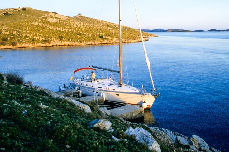 Ein Segelboot auf dem Wasser mit einer Küstenlinie im Hintergrund.