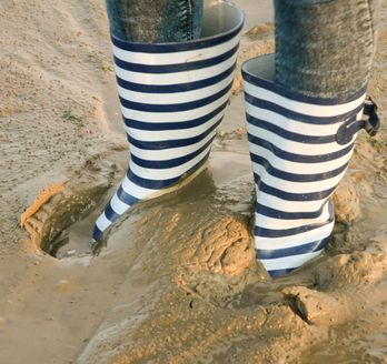 Eine Person trägt gestreifte Hosen und ist teilweise im Sand vergraben.