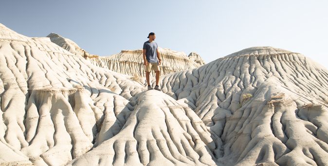 Ein Mann steht auf einem Felsen im Dinosaur Provincial Park in Alberta