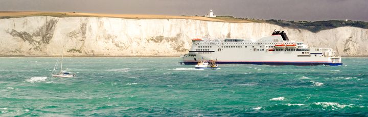 Ein Passagierschiff gleitet auf ruhigem Wasser. Ein weiteres kleines Boot fährt in der Ferne.