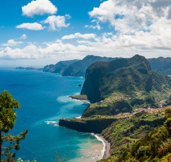 Eine Küstenlandschaft mit Klippen, die ins blaue Meer abfallen, und einer Stadt am Ufer.
