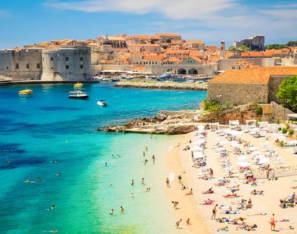 Ein Sandstrand mit türkisfarbenem Wasser und einem Boot.