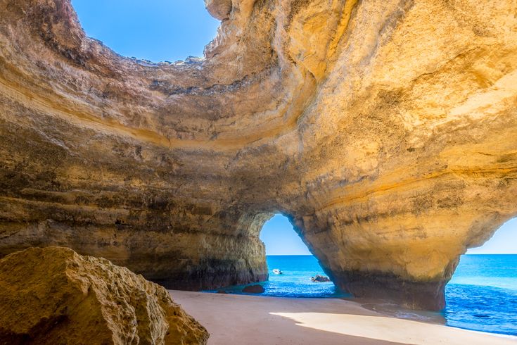 Eine natürliche Höhle mit einem Bogen, der zum Meer führt, beleuchtet von der Sonne.