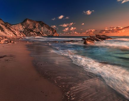 Ein Strand mit türkisfarbenem Wasser und einem bewölkten Himmel.