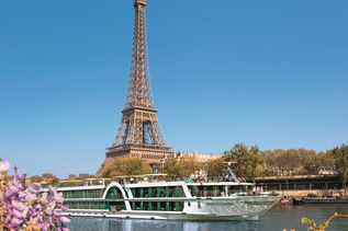 Ein Kreuzfahrtschiff fährt auf der Sein in Frankreich mit Eiffelturm im Hintergrund