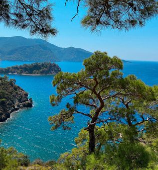  Atemberaubende Aussicht auf die Bucht von Fethiye in der Türkei, mit einer malerischen Küstenlinie, türkisblauem Wasser und bewaldeten Hügeln unter einem klaren Himmel.