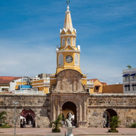 Die Puerta del Reloj (Uhrentor) in Cartagena de Indias, Kolumbien, ein historisches Wahrzeichen mit einem markanten Uhrturm und einer Reihe von bunten Kolonialgebäuden.