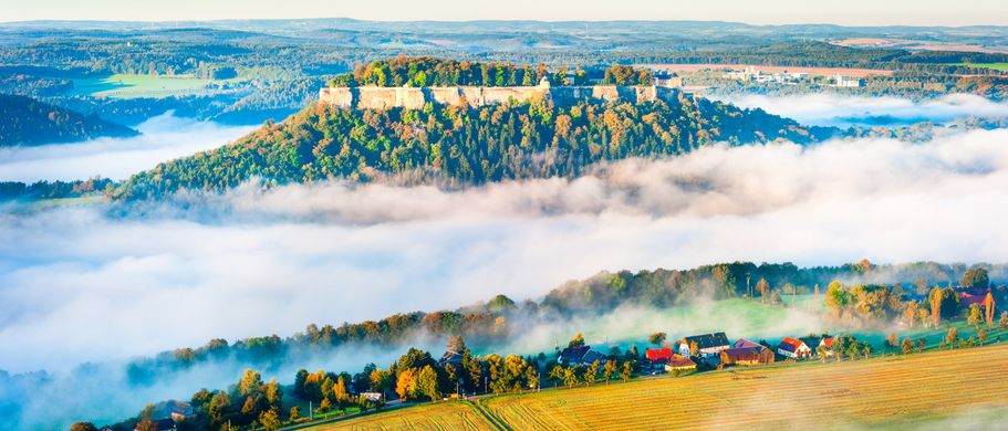 Festung Königstein thront auf einem Felsen über der Elbe, die hier unter den Wolken verschwindet