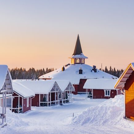 Mit Schneebedeckte rote Häuser Siedlung im Sonnenaufgang in Finnland