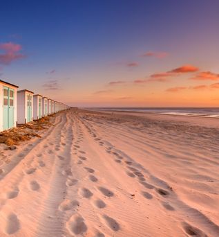 Ein Strand mit kleinen Strandhütten und einem Weg.