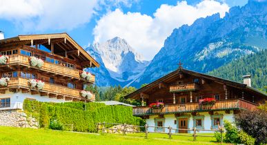 Zwei Häuser mit Alpen im Hintergrund