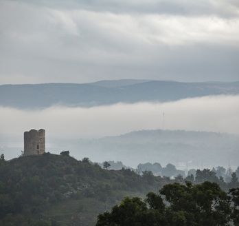 Eine alte Burgruine auf einem Hügel, umgeben von grünen Bergen.