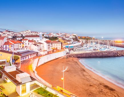 Eine Küstenstadt mit einem langen Sandstrand und einem Hafen.