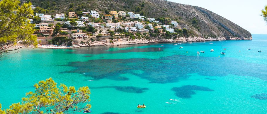 Bucht mit türkisblauem Wasser und Häusern an der Küste in Spanien. 