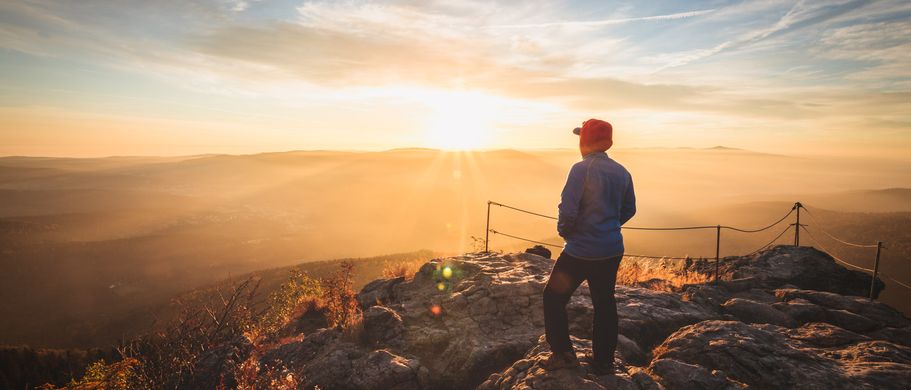 Urlaub im deutschen Mittelgebirge Bayerischer Wald Wanderer auf Gipfel mit Sonnenuntergang