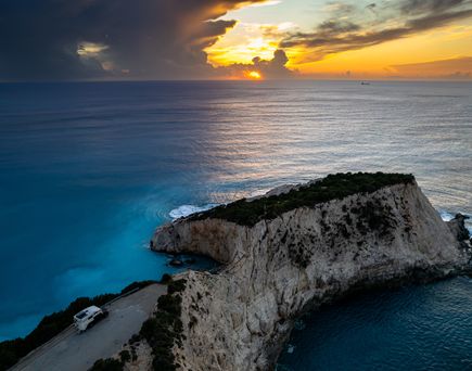 Luftaufnahme eines Sonnenuntergangs über dem Meer auf einem Wohnmobilparkplatz an der Steilküste von Lefkada, Griechenland.