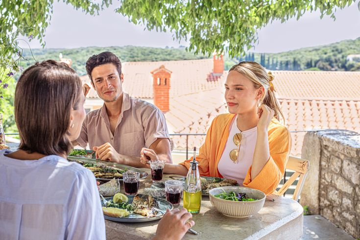 Drei Menschen beim Essen mit Wasser im Hintergrund