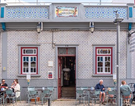 Haus in Portimao Portugal mit Personen, welche vor dem Haus an Tischen sitzen und sich unterhalten.