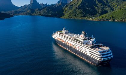 Ein Kreuzfahrtschiff fährt durch einen Fjord, umgeben von steilen Bergen.