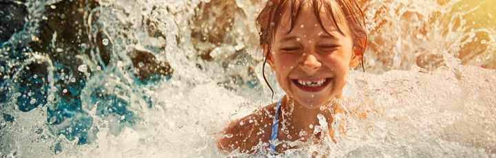 Lachendes Kind im Schwimmbad eines Wasserparks.