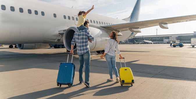 Familie mit Koffern am Flugzeug
