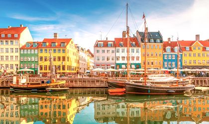 Farbenfrohe Giebelhäuser und historische Segelboote im Hafenviertel Nyhavn in Kopenhagen bei blauem Himmel.