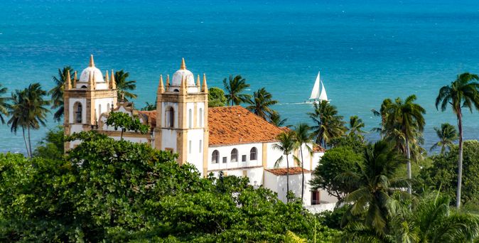 Igreja de CArmo Blick über Palmen auf die Kirche. Im Hintergrund das Meer