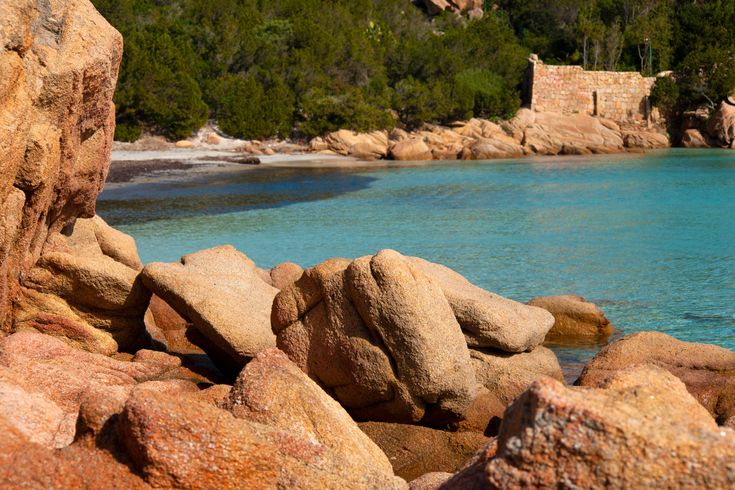Ein Strand mit türkisfarbenem Wasser und Felsen.