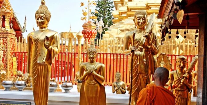 Buddhistische Mönche in orangefarbenen Roben, die in einem Tempelkomplex gehen.