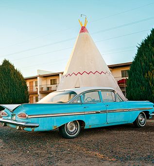 Türkisfarbener Oldtimer mit Tippi Zelt im Hintergrund