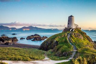 Weg mit Stufen zum Mawr Leuchtturm in Wales in England und im Hintergrund Meer und Berge