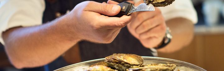 Person isst frische Austern und Meeresfrüchte an einem Tisch in einem schwedischen Restaurant.