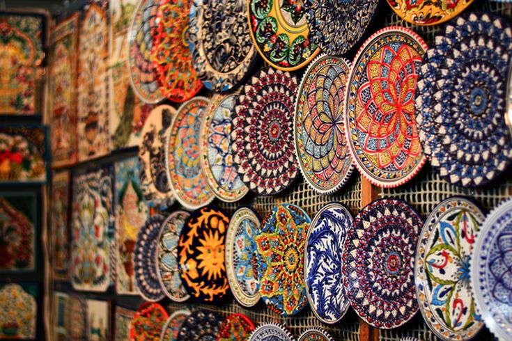 Detailreich bemalte Keramikteller in leuchtenden Farben schmücken die Wand eines kunstvollen orientalischen Marktes.