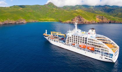 Das Schiff Aranui 5 im Meer, im Hintergrund grüne Berglandschaft