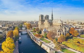 Eine Luftaufnahme von Paris mit dem Eiffelturm, der Seine und Gebäuden. Die Stadt erstreckt sich weitläufig und zeigt ihre ikonischen Wahrzeichen.