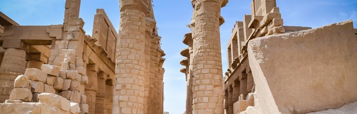 Eine archäologische Stätte in Luxor, die von einer großen Säulenreihe und alten Strukturen umgeben ist.