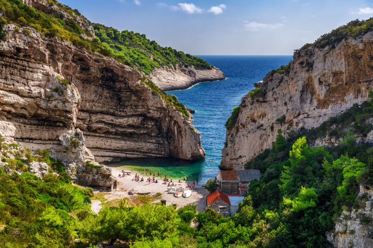 Eine felsige Bucht mit einem Strand und türkisfarbenem Wasser.