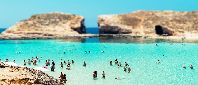 Ein felsiger Strand mit flachem türkisfarbenem Wasser.