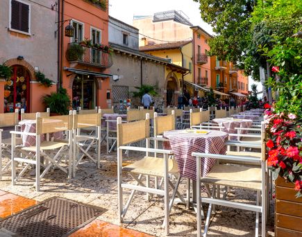 Gastronomie am Gardasee. Stühle und Tische in der Stadt, umgeben von alten kleinen schnuckeligen Häusern.