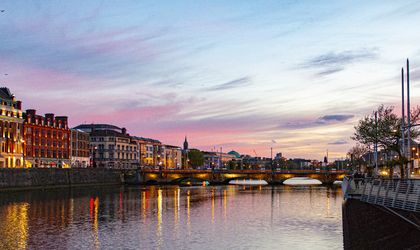 Ein Fluss mit Gebäuden am Ufer bei Sonnenuntergang.