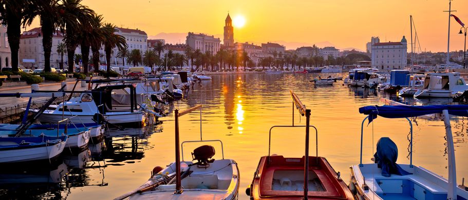 Eine malerische Küstenansicht von Split, Kroatien, bei Sonnenaufgang, mit der Stadt, die sich am Ufer des Adriatischen Meeres ausbreitet, und Bergen im Hintergrund.