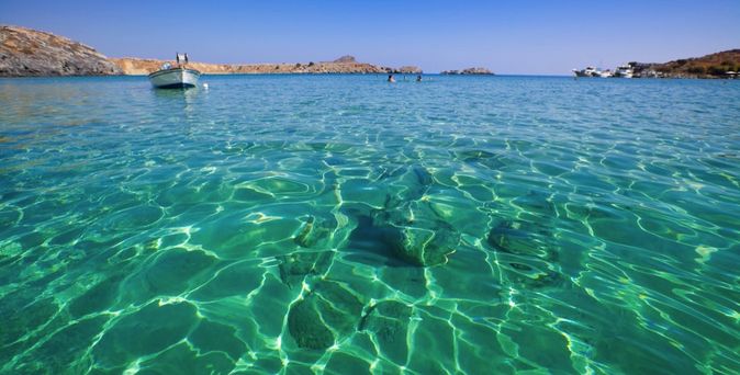 Ein Sandstrand mit türkisfarbenem Wasser und einem Boot.