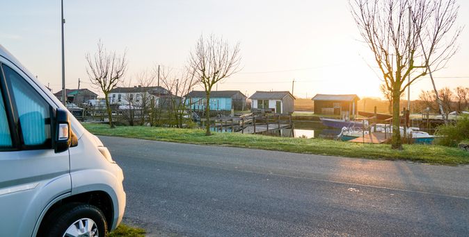 Ein weißes Fiat Ducato Wohnmobil ist auf einer Landstraße in Somerset zu sehen, umgeben von grünen Feldern und Bäumen unter einem bewölkten Himmel.
