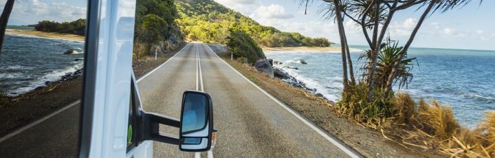 Blick aus einem fahrenden Camper auf eine Küstenstraße
