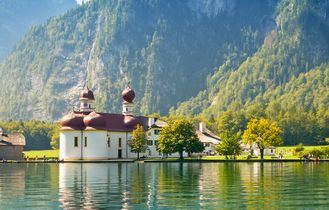 Ein See mit Bäumen und Bergen.