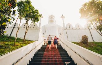Zwei Menschen besteigen Treppen zu weißem Tempel