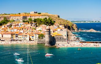 Luftaufnahme der Küstenstadt Collioure in Languedoc-Roussillon, Frankreich, mit Festung, Strand und Booten im Meer.