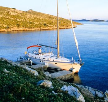 Ein Segelboot auf dem Wasser mit einer Küstenlinie im Hintergrund.