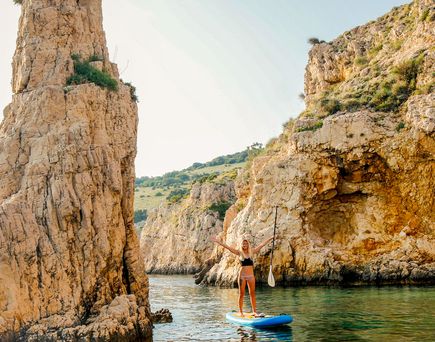 Kroatien Strand Urlaub Istrien Frau auf Surfboard zwischen Felsen