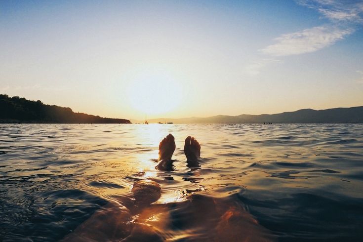 Zwei Personen schwimmen im Meer bei Sonnenuntergang.